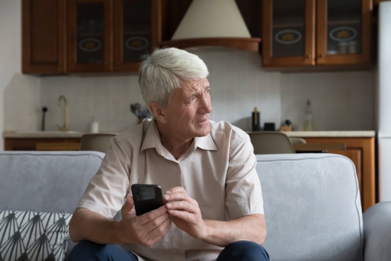 What’s That Smell Coming From My Furnace? Photo of an elderly man looking out a window, sitting on his couch.